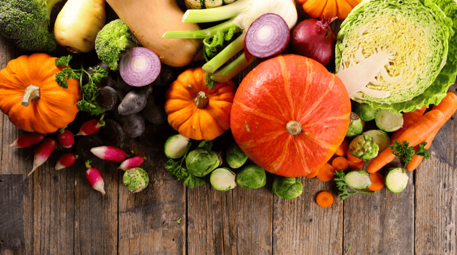 photo de légumes d'automne avec 3 courges dont 2 petites et une grosse, un demi chou blanc, des radis , des choux de bruxelles, un fenouil, des carottes entières et coupées en rondelles, 2 demi oignons rouges