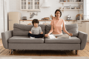 photo d'une maman et son fils en position de yogi sur un canapé gris
