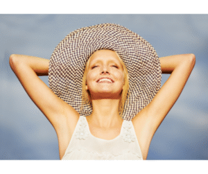 Photo d'une femme souriant les bras derrière son chapeau de paille