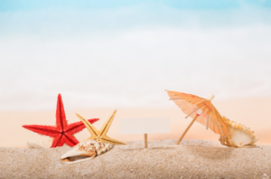 Image de sable fin avec une étoile de mer rouge et un jaune, un petit parasol en papier