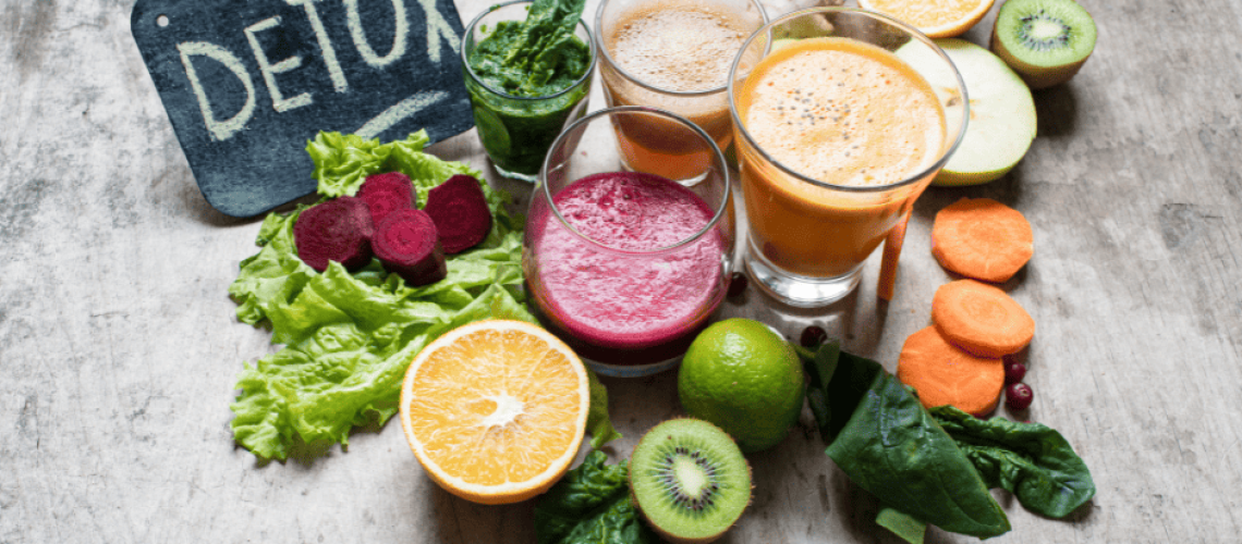 sophrologie-naturopathie-détox photos de fruits et légumes avec 4 verres de smothies au centre en haut à gauche, il y a une ardoise sur laquelle il est écrit DETOX il y a 1 verre de smoothie vert avec une petite feuille d'épinard au-dessus, un orange avec quelques rondelles de carottes à côté, un smoothie brun avec un morceau de gingembre et une demie orange à côté, un demi kiwi et une demie pomme et un smoothie rouge avec des morceaux de betteraves sur une feuille de salade à côté et une demi orange, un demi kiwi et un citron vert