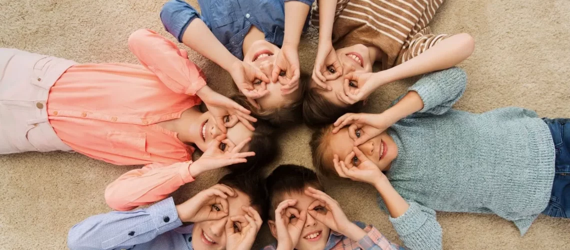 sophrologie-naturopathie-Enfant photo d'enfants allongé en formant un cercle, ils entourent leur yeux avec leur main pour faire des lunettes