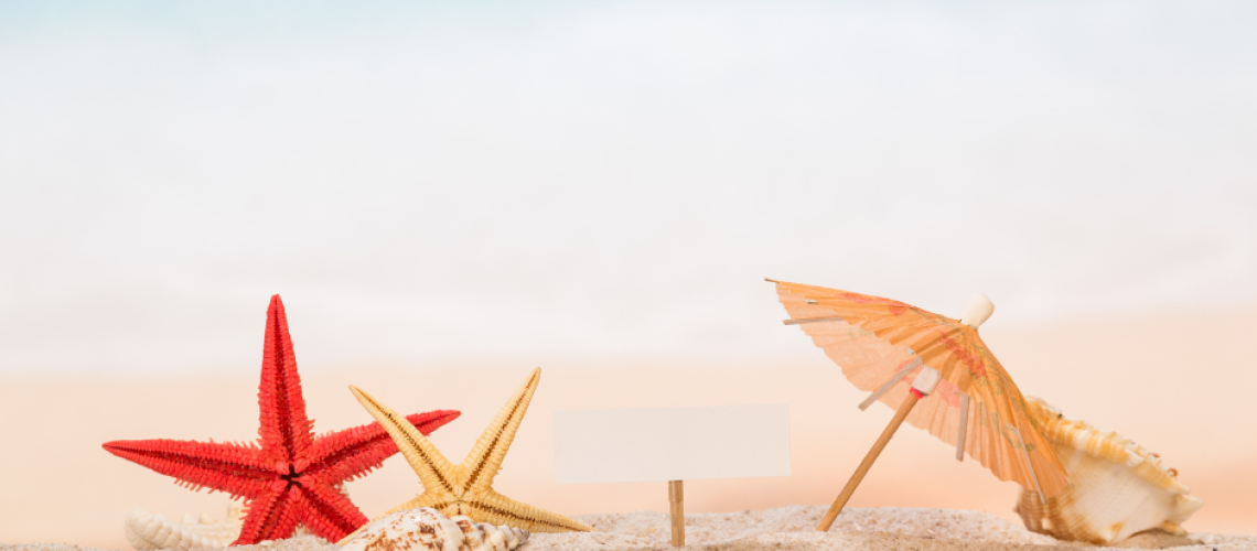 Image de sable fin avec une étoile de mer rouge et un jaune, un petit parasol en papier